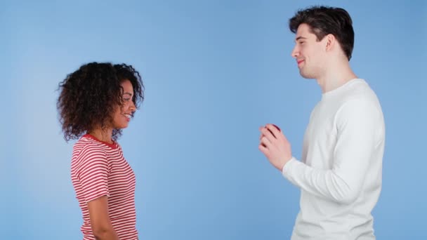 Joven pareja Interracial. Hombre hace propuesta de matrimonio a su amante mujer africana con anillo en fondo de estudio azul. Amor, relación, concepto de felicidad. — Vídeo de stock
