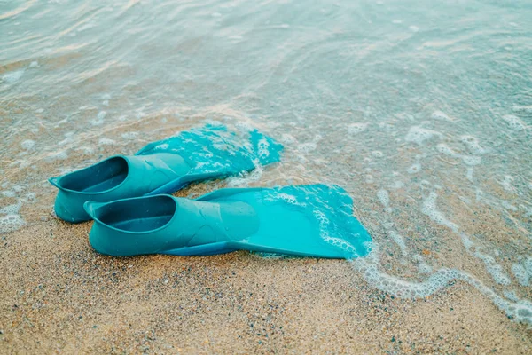 Pair of teal flippers on sandy sea or ocean beach, side view. Swimming equipment - fins on shore. Summer vacation, fun, exploration of marine world concept — Stock Photo, Image