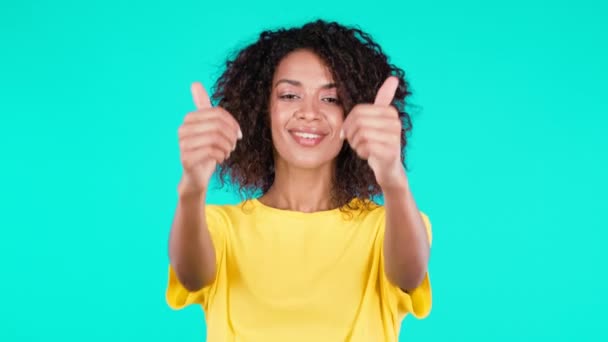 Afrikaanse vrouw toont als duim omhoog teken op teal studio achtergrond. Positief jong gemengd ras meisje glimlacht voor de camera. Winnaar. Succes. Lichaamstaal. — Stockvideo