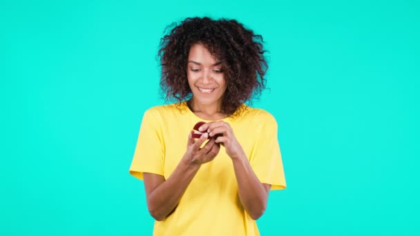 Decepcionada mujer africana molesta, no le gusta el regalo. Bonita dama sosteniendo pequeña caja de joyería con propuesta de matrimonio sobre fondo verde azulado. — Vídeos de Stock