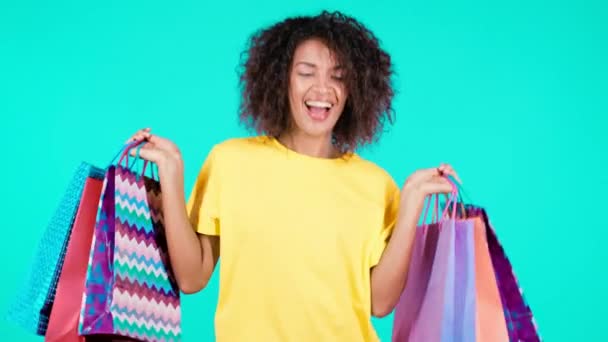 Excited african woman with colorful paper bags after shopping on teal studio background. Concept of seasonal sale, purchases, spending money on gifts — Stock Video