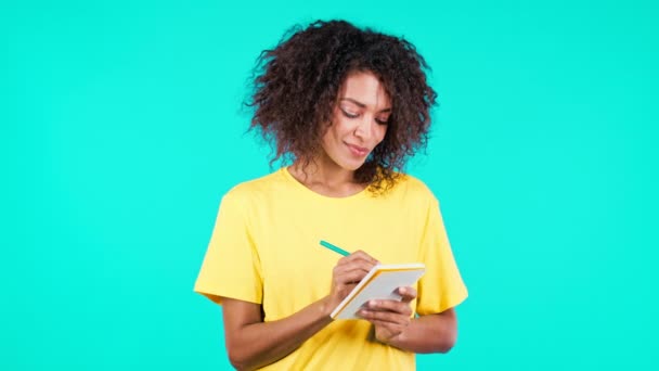 Jonge vrouw maakt notities in planner, Afrikaanse dame met pen. Ze schrijft toekomstplannen en to-do lijstje in notitieboekje voor week of maand. Het bijhouden van persoonlijke dagboek op teal studio achtergrond. — Stockvideo