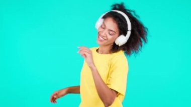 Teal stüdyosunda kablosuz kulaklıkla dans eden çekici bir kadın. Tatlı Afrikalı Amerikalı kız dans ediyor ve gülümsüyor. Müzik, radyo, mutluluk, özgürlük, gençlik kavramı.