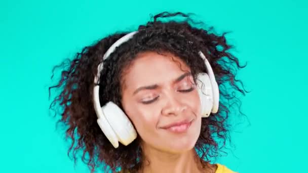 Aantrekkelijke vrouw dansen met draadloze hoofdtelefoon op teal studio achtergrond. Schattig Afrikaans Amerikaans meisje dat danst en lacht. Muziek, radio, geluk, vrijheid, jeugdconcept. — Stockvideo