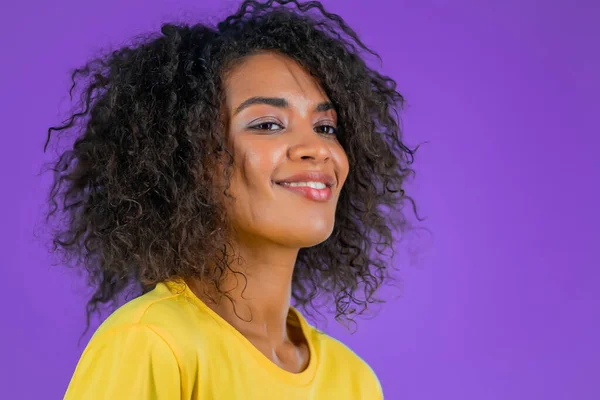 Freundliche Mischlingshündin mit lockiger Frisur im gelben T-Shirt. Afrikanische Dame auf lila Studiohintergrund. — Stockfoto