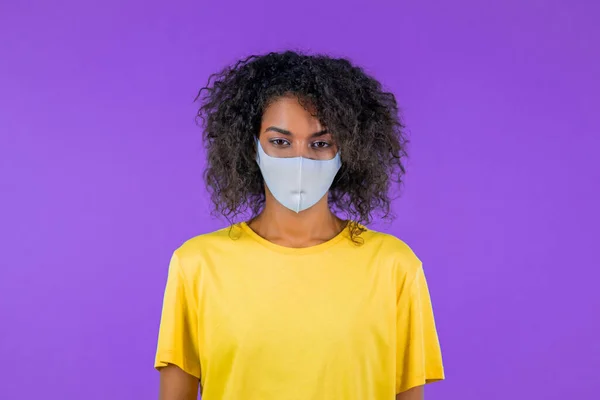 Mujer africana con máscara de protección médica facial, concepto de cuarentena. Estudio púrpura fondo. — Foto de Stock