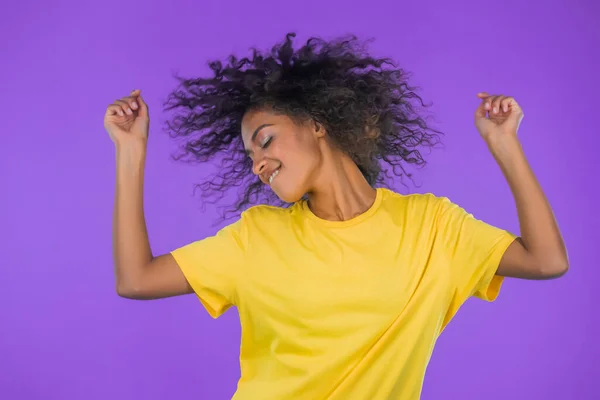 Szczęśliwy kręcone włosy afrykańska kobieta taniec, zabawy, raduje się na fioletowym tle studio. Mistrzyni. Koncepcja świętowania, imprezy, zwycięstwa — Zdjęcie stockowe