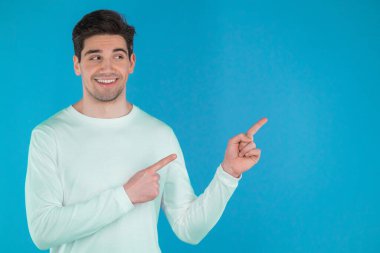 Mutlu gülümseyen adam mavi arka planda izole edilmiş bir şey sunuyor ve gösteriyor. Adamın portresi, kollarını sol tarafında fotokopi aletiyle gösteriyor..