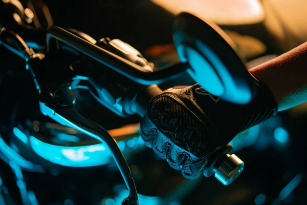 Motorcyclist hand wearing leather gloves twists accelerometer lever in colored city lights. handlebars of motorcycle. Nightlife and biker culture concept. — Stock Photo, Image