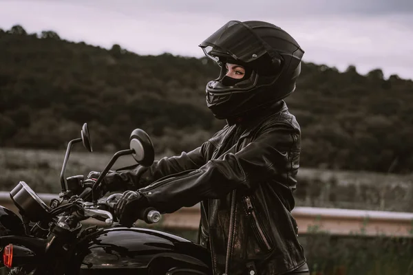 Ritratto di donna motociclista sicura di sé in casco da moto. Giovane motociclista che guarda dall'esterno da solo sull'autostrada. Pronti per il viaggio. Cafe corridori, moto estetica e design vintage concetto. — Foto Stock