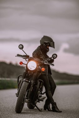 Motosikletli kadın portresi cep telefonu kullanıyor, akıllı telefon kullanıyor. Genç bir motorcu seyir subayı kullanıyor..
