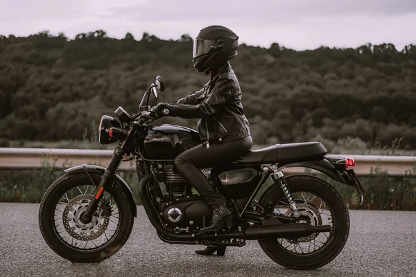 Portrait de femme motocycliste confiante en casque de moto. Jeune motard conducteur regardant loin à l'extérieur seul sur l'autoroute. Prêt pour le voyage. Café coureurs, esthétique moto et concept de design vintage. — Photo