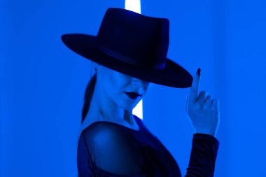 Tanımlanamayan seksi kadın, koyu renkli mavi ışıkla koyu renkli neon stüdyo arka planında parmak uçlarında koşuyor. Ölümcül kadın, şık balerin kıyafeti..