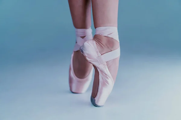 Dançarinos de balé pés em sapatos pontiagudos close-up, ela posando em dedos do pé isolados no fundo do estúdio azul. Pernas de mulheres bonitas. Bailarina irreconhecível. — Fotografia de Stock