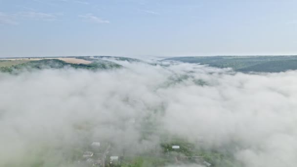 Sisli bir sabahta dağların arasındaki vadideki küçük bir köyde hava aracı görüntüsü. Vadide sis var. Doğa arkaplanı. — Stok video