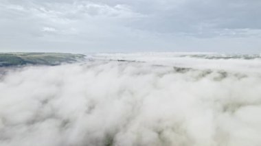 Sisli bir sabahta dağların arasındaki vadideki köy ya da şehir üzerindeki hava aracı görüntüsü. Vadide sis var. Doğa geçmişi, sakinlik, yalnızlık, yeryüzü konseptinin güzelliği.