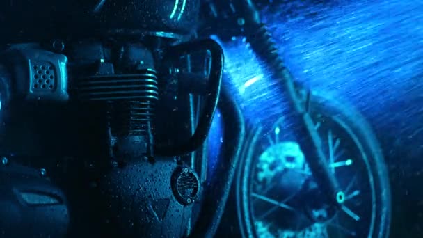 Мотоцикл в стиле ретро на стирке под неоновым голубым светом. Стирка с водой детали классического черного мотоцикла. В стиле Каферасеров. Техническое обслуживание автомобилей — стоковое видео