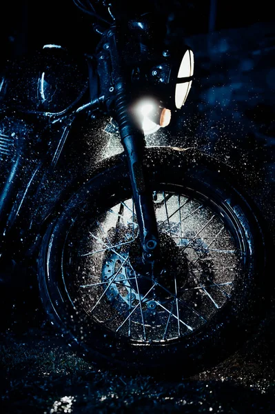 Vintage styled motorcycle on washing. Blue illumination at night. Splashing water on front wheel with disc brakes. Classic black motorbike. Caferacers style. Maintenance of motor vehicles — Stock Photo, Image