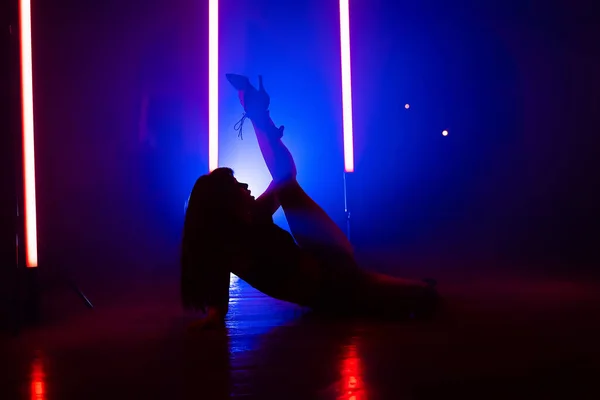 Silhuett av vacker dansare på rökig flerfärgad bakgrund. Neon spotlight lyser bakom sexig kvinna. Damen rör sig förföriskt. Begreppet koreografi, dans, performance — Stockfoto