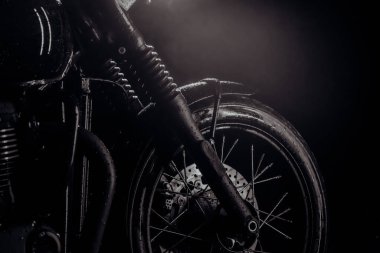 Motorcycle with water drops at night. Front wheel with disc brakes. Classic black motorbike. Caferacers style. Maintenance of motor vehicles.