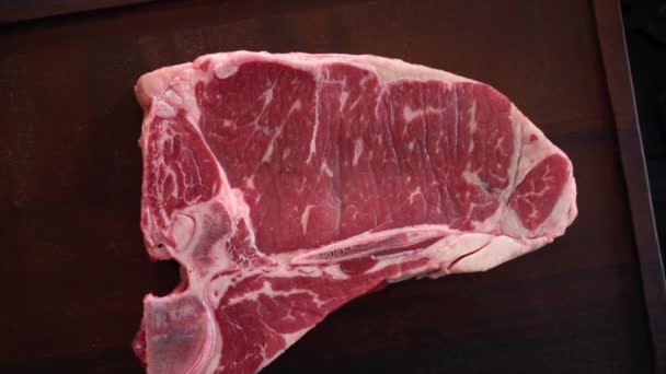 Rotating T-bone steak - raw marble beef fillet, aged prime rare delicious juicy meat. Top view. Presentation of dish in luxury restaurant. — Stock video