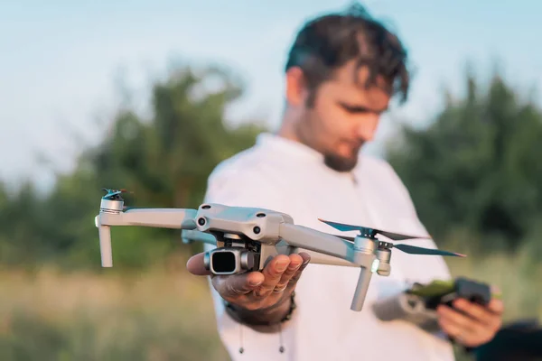 Homme tenant un drone amateur compact avant le vol. Piloter un quadcoptère à l'extérieur. Fusillade aérienne. Filmer la nature d'en haut — Photo