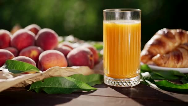 Colazione sana - pesche mature, croissant e vetro di succo recentemente premuto sul tavolo. Cibo vegetariano, vitamine, raccolto estivo da albero da frutto. — Video Stock