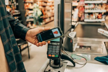 Müşteri kasiyerden yiyecek alıyor ve kasadan ödeme yapıyor. Süpermarket. Marketteki akıllı telefondan erişimi olmayan kredi kartıyla ödeme yapan adam.
