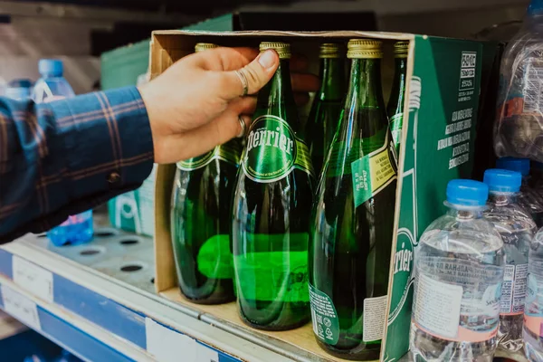 Odessa, Ukraine - August 2021. Der Mensch wählt Mineralwasser in einem Geschäft. Perrierflasche. — Stockfoto