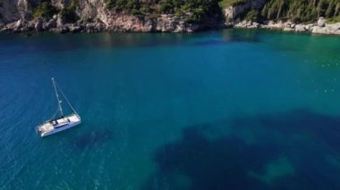 Demir atmış tekneyle mavi deniz suyunu temizlemek için hava aracı görüntüsü. Şaşırtıcı gök mavisi arka plan. Güney Avrupa adasında özel plaj, lüks seyahat manzarası