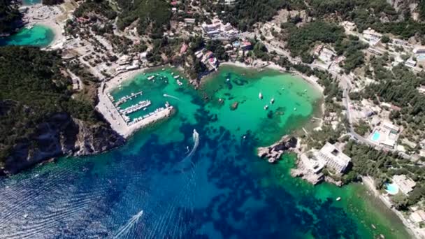 Vista aérea del dron a la bahía de Paleokastritsa, costa en forma de corazón con agua de mar de teca clara. Grecia Isla de Corfú. Villa de lujo, barcos, yates. Increíble paisaje marino europeo. — Vídeos de Stock
