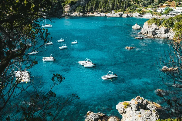 Rovinia beach view with clear blue sea water and moored boats. Amazing azure nature background. Private coast on Greece Corfu island, luxury travel sight — Stock Photo, Image