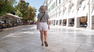 Korfu, Yunanistan - Eylül, 2021. Kerkyra 'da Liston Caddesi' nde yalnız yürüyen bir kadın. Tarihi binanın güzel cephesi. Yaz sezonu. Genç turist bayan yerel mimariyi geziyor..