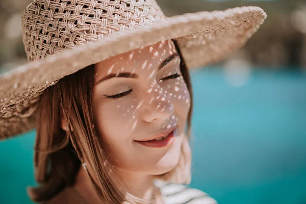 Bella donna in cappello di paglia sorridente sinceramente su sfondo blu mare. Ragazza godendo di aria fresca, brezza. Lady sulla destinazione di viaggio di lusso, concetto di stile di vita di vacanza. — Foto Stock