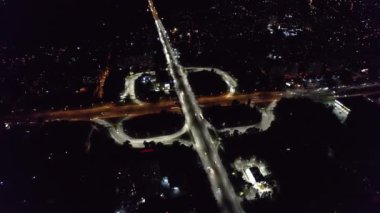 Roundabout Lane 'deki hava aracı görüntüsü, Gece Kenti kavşağındaki trafik. Çok katlı otoyolda giden arabalar ve kamyonlar. Ulaşım, altyapı geliştirme kavramı.