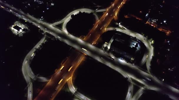 Aerial drone top view at roundabout lane, traffic on junction of night city. Cars and trucks driving on multi-level highway. Transportation, infrastructure development concept. — Stock Video