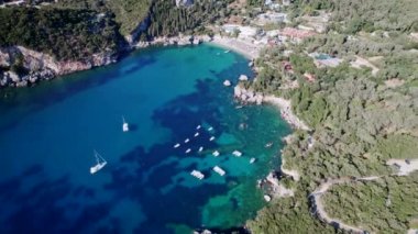 Mavi deniz suyunu, demirli tekne ve yatlarla temizlemek için hava aracı görüntüsü. Şaşırtıcı gök mavisi arka plan. Yunanistan 'ın Corfu Adası' ndaki özel plajda demirleme sahaları.