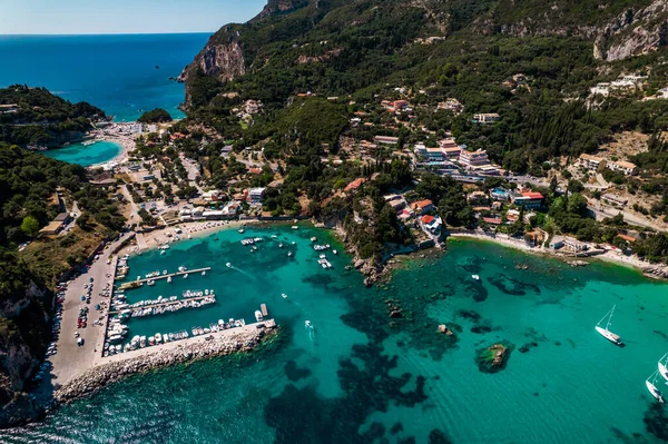 Aerial drone view to Paleokastritsa bay, heart-shaped coast with clear teal sea water. Greece Corfu island. Luxury resort village, boats, yachts. Amazing european seascape. — Stock Photo, Image