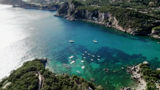 Letecký dron pohled na čistou modrou mořskou vodu s kotvící lodě a jachty. Úžasné azurové přírodní pozadí s korálovými útesy. Ukotvení v zátoce na soukromé pláži na ostrově Korfu, Řecko cestovní destinace. — Stock video