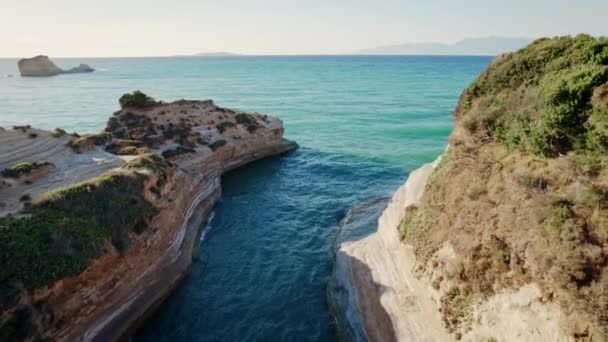 캐널 다 모어 (Canal DAmore) - 사랑의 통로. 공중 드론 이 청록색 바닷물 이 있는 낙원 해변으로 향하고 있습니다. 코 푸 섬, 그리스. 높은 가파른 절벽 이 있는 시가지 — 비디오