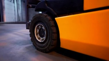 Depoda çalışan bir yükleyicinin tekerlerine yakın çekim. Elektrikli forklift - Üretimde yararlı ekipman.