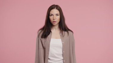Ciddi bir kadın baş işareti olmadan onaylamıyor, onaylanmayacak şekilde başını sallıyor. Reddetmek, reddetmek, anlaşmazlık pembe arka planda güzel bir bayanın portresi. Yüksek kalite 4k görüntü