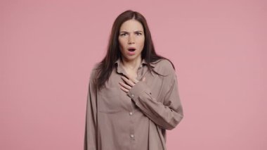 Genç kadın, pembe arka planda korku dolu büyük gözlerle kameraya bir şeyden korkarak şok geçirdi. Fobi, sorun, panik konsepti. Yüksek kalite 4k görüntü