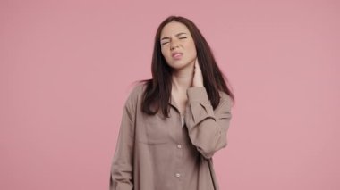 Yorgun genç bir kadın boyun eklemlerinde ağrı hissediyor, kaslara masaj yapıyor, başını ovuyor. Kireçlenme yüzünden rahatsızlığı olan bir bayan. Sağlık hizmeti, tıbbi konsept. Yüksek kalite 4k