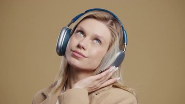 Müzik dinleyen mutlu kadın, pembe stüdyo arka planında kulaklıklarla dans ediyor. Radyo, kablosuz modern ses teknolojisi, çevrimiçi çalar. Yüksek kalite 4k