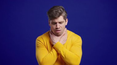 Adamın yarası var. Mavi Stüdyoda Şişmiş Boğazlı Hasta Adam. Anjin. Genç öğrenci acı hissediyor, acı çekiyor. Mevsimsel grip, soğuk algınlığı. Yüksek kalite 4k görüntü