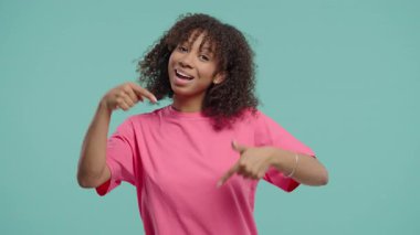 Genç kadın blogcu reklam alanını işaret ediyor. Mavi arka plan. Güzel genç kız aşağıda üye olmak için tıklamak istiyor. Ticari fikir ve tanıtım içeriği için kopyalama alanı. Yüksek kalite 4k 