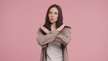 Hayır, asla, güzel bir kadın el işaretini keserek jestten hoşlanmaz ve reddeder. Onaylamayan şirin bir kız pembe stüdyo arka planında inkar işareti yapıyor. Ban, mola. Yüksek kalite 4k