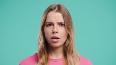 Ciddi bir kadın baş işareti olmadan onaylamıyor, onaylanmayacak şekilde başını sallıyor. Reddetmek, reddetmek, anlaşmazlık, mavi arka planda güzel bir bayanın portresi. Yüksek kalite 4k görüntü