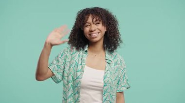 Afrikalı kadın model parlak bir ifadeyle açıkça el sallıyor. Vedalar, sıradan selamlar, duygusal sonlar, sıcak iletişim.
